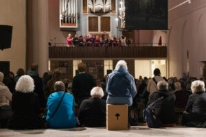 Viele Menschen sitzen in der Kulturkirche St. Stephani, man sieht ihre Rücken, sie schauen zur Empore, auf der ein Chor singt