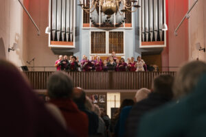 Ein Chor in lilafarbener Kleidung singt von der Empore der Kulturkirche St. Stephani