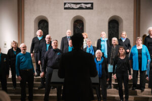 Ein Chor in schwarz-blauer Kleidung singt auf den Altarstufen in der Kulturkirche St. Stephani