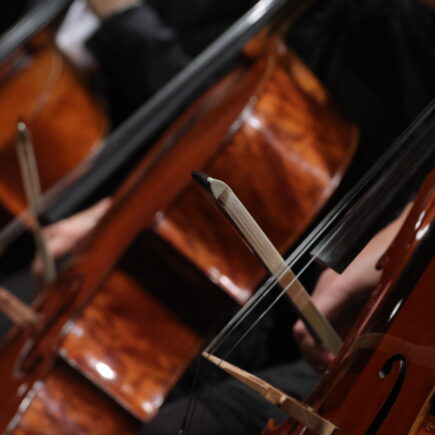 Detailaufnahme von drei Violoncelli, mit dem Bogen gespielt werden