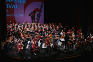 Ein großes Orchester aus 200 Menschen musiziert auf der Bühne des Stadttheaters.