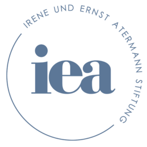 In blaugrauer Schrift auf weißem Grund sind die Buchstaben i e a zu sehen, in kreisförmiger Anordnung steht darum herum angeordnet: Irene und Ernst Atermann Stiftung